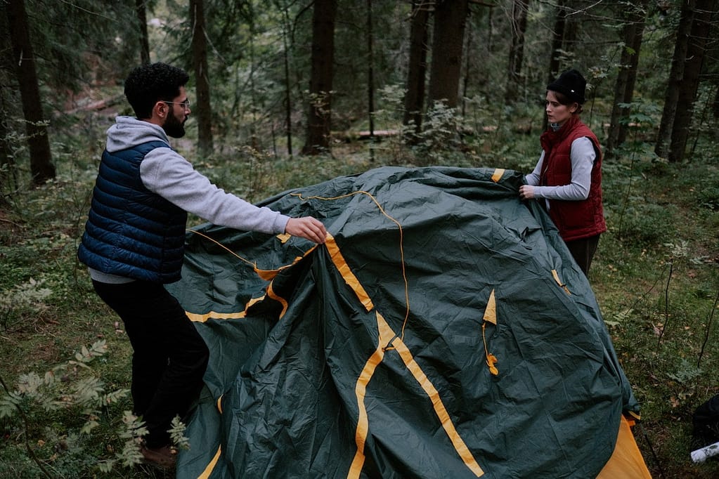 Man and woman setting up a tent in camp