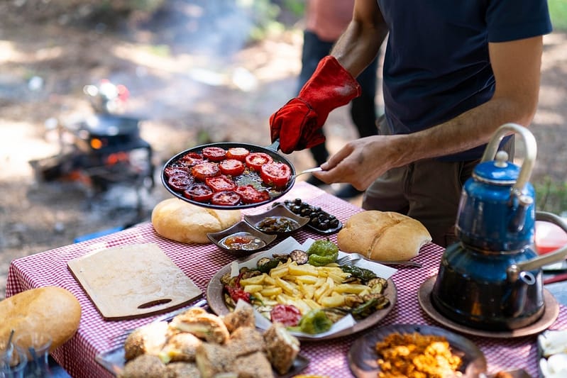 Man preparing a meal while camping near campfire