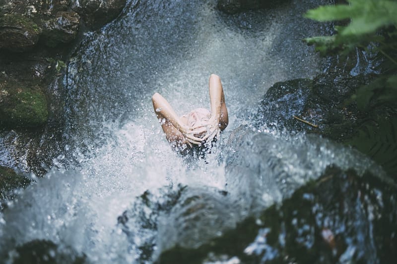 Woman taking shower in neture under a waterfall