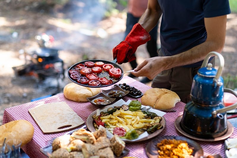 Man preparing a meal while camping near campfire