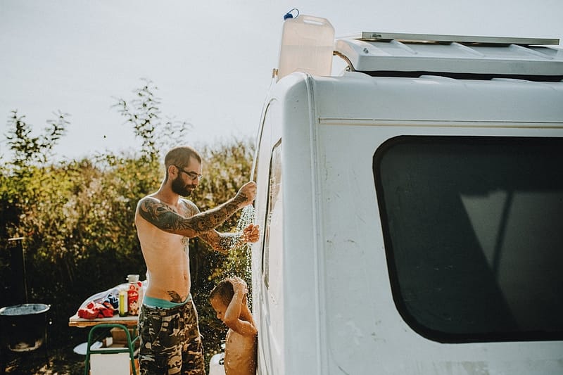 A man showers his son with a DIY Overland Shower